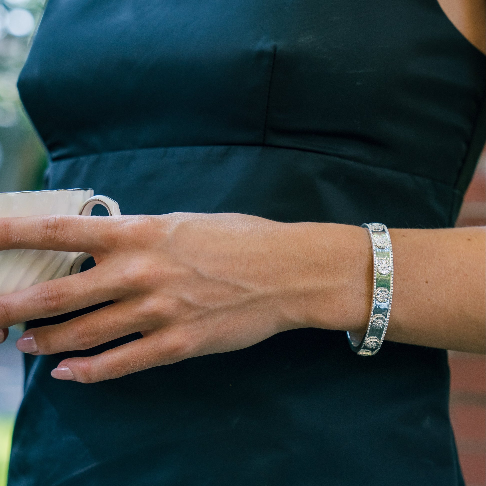 Person wearing a dark green dress holding a cup outdoors